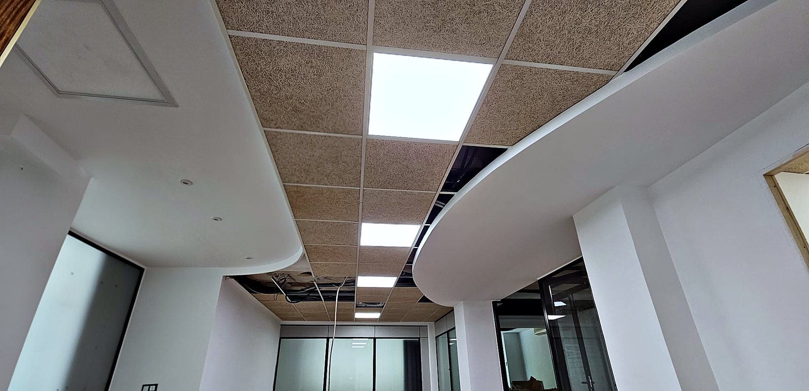 Techo curvo de pladur con bajadas y paneles acústicos en una oficina